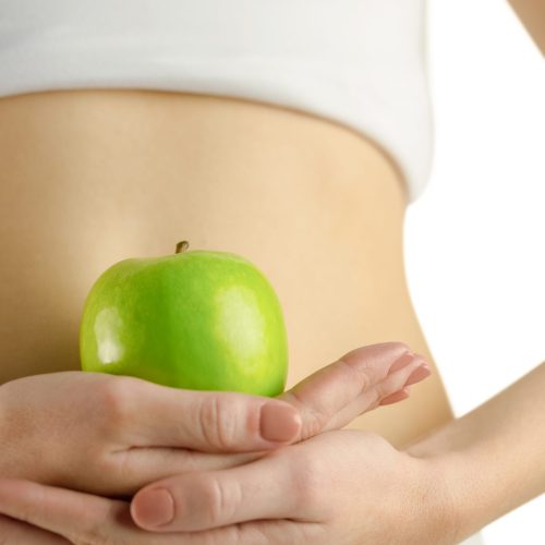 Slim woman holding green apple on white background