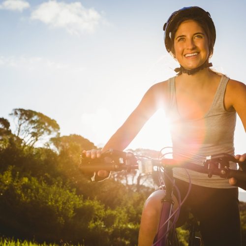 Smiling athletic brunette sitting on mountain bike in the nature